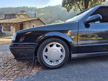 Un coche negro está aparcado al costado de la carretera.