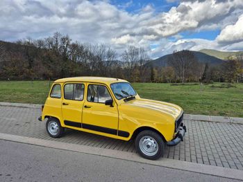 Un coche amarillo está aparcado al costado de la carretera.