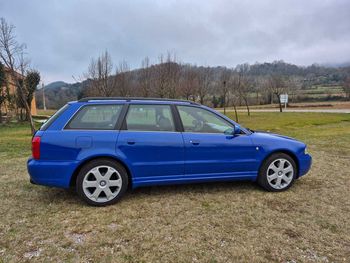 Un coche azul está aparcado en un campo de hierba.