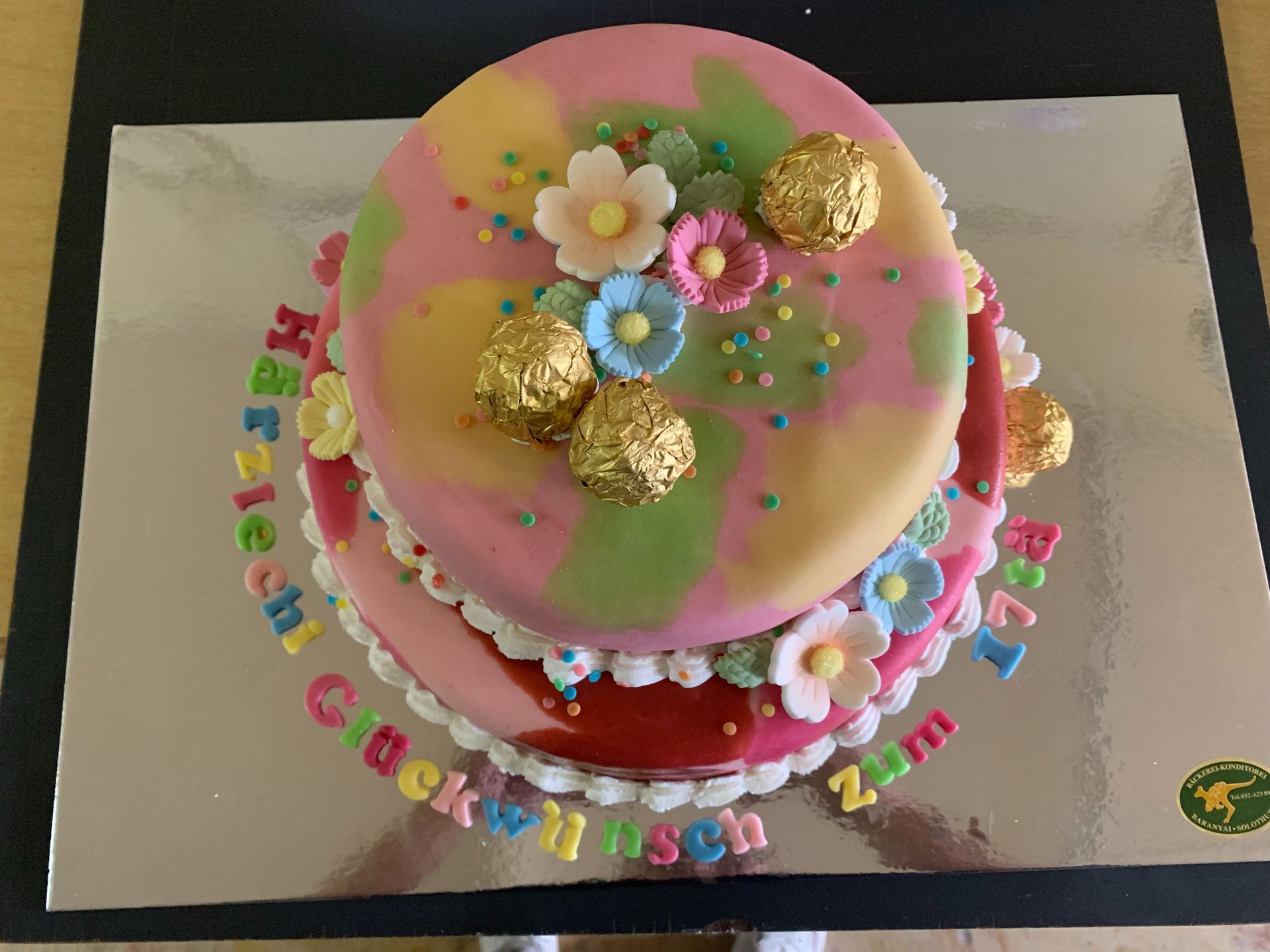 Eine bunte Geburtstagstorte mit Blumen und Streuseln obendrauf