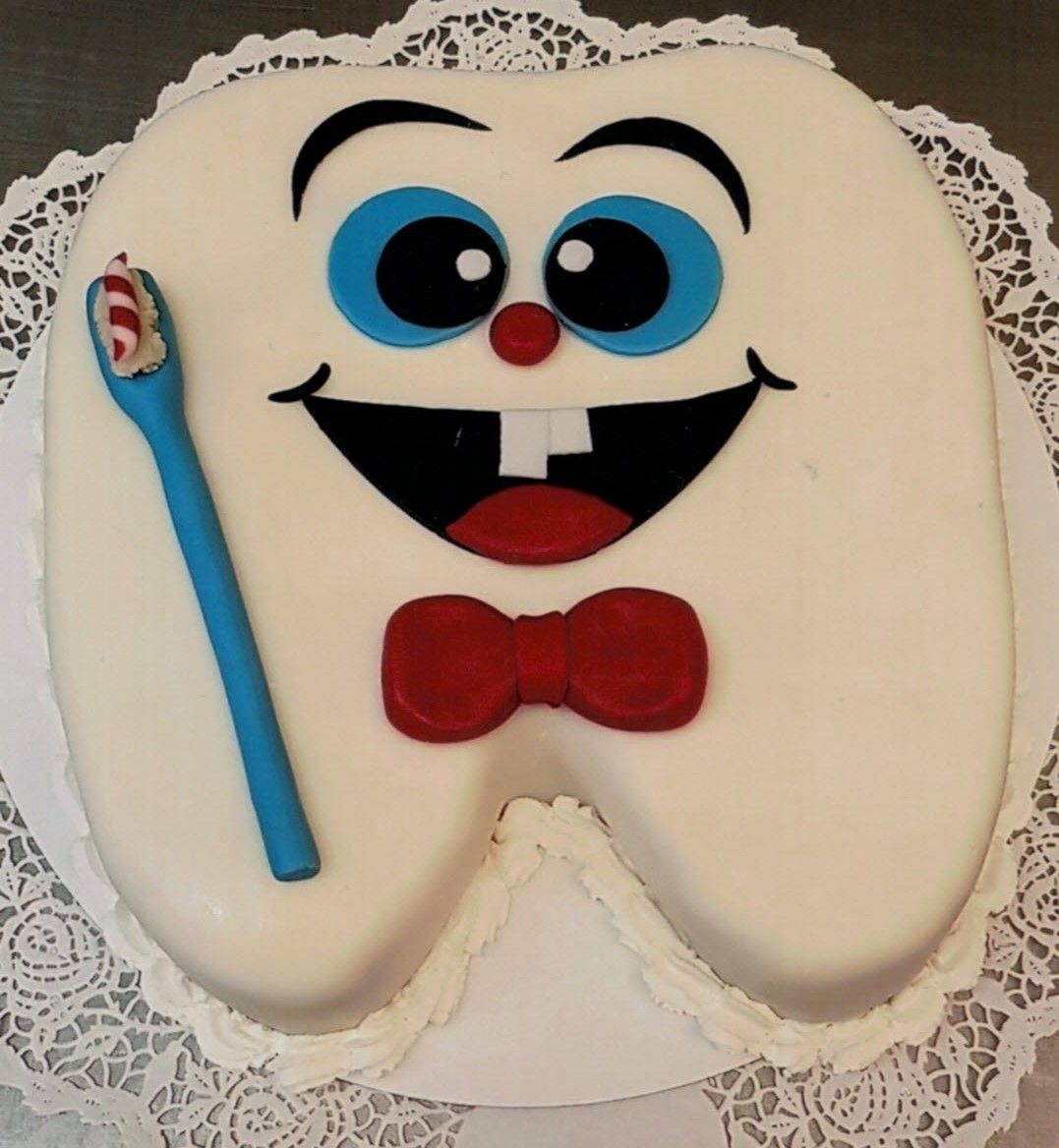 Ein Kuchen in Form eines Zahns mit einer Zahnbürste und einer Fliege