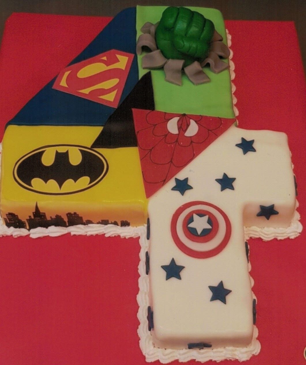 Eine Torte mit der Nummer vier und Superman, Batman, Captain America und Hulk darauf