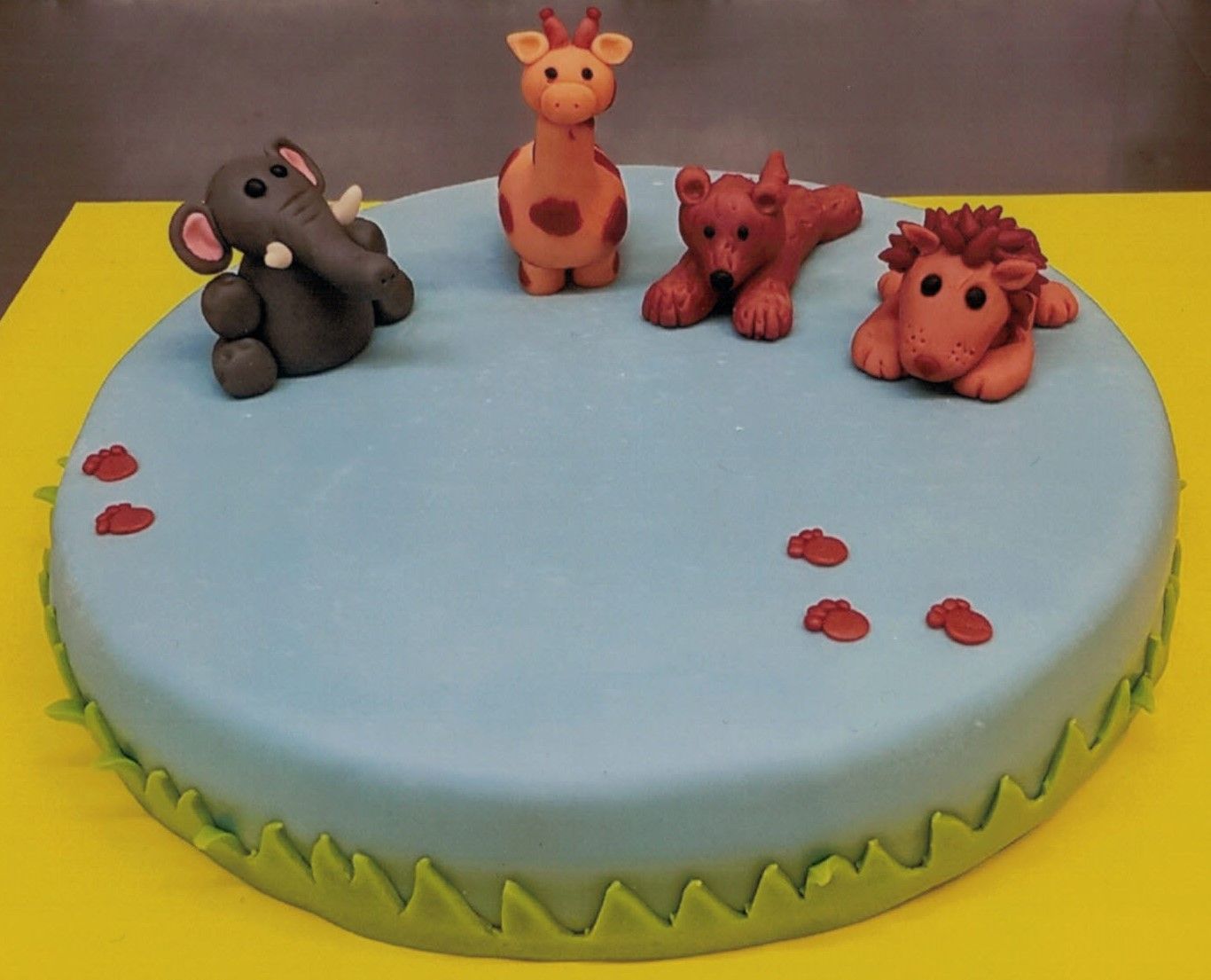 Ein Kuchen mit Tieren darauf, darunter ein Elefant, eine Giraffe und ein Löwe