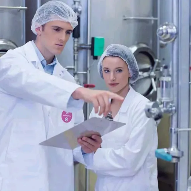 Un hombre y una mujer con batas de laboratorio miran un portapapeles.