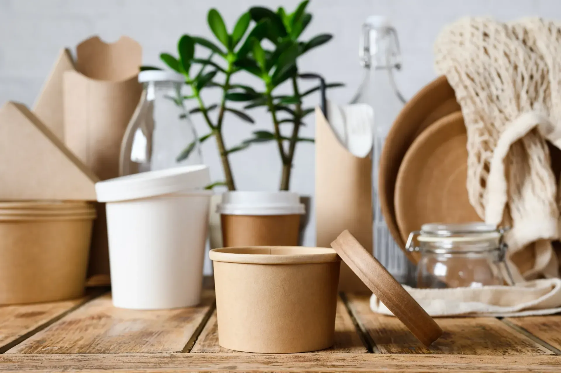 Una mesa de madera cubierta con una variedad de recipientes de papel y vidrio.
