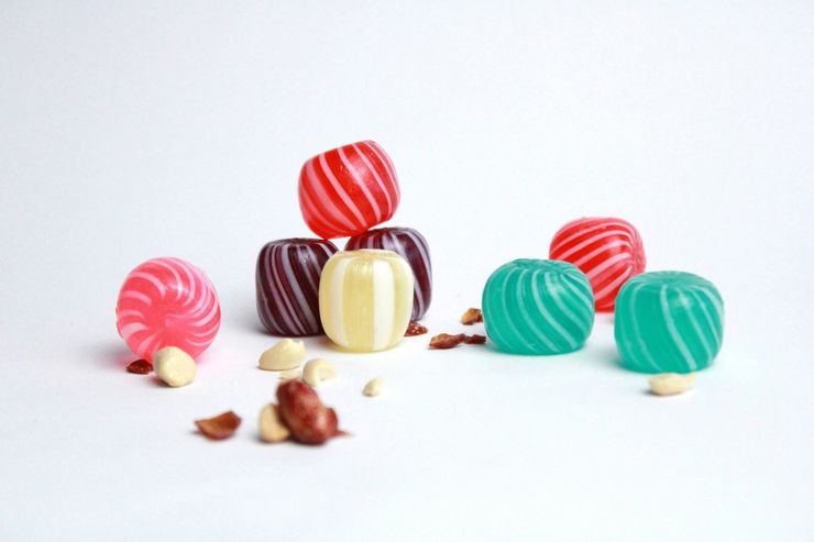 Caramelos a rayas de colores dispuestos sobre una superficie blanca con migas esparcidas.