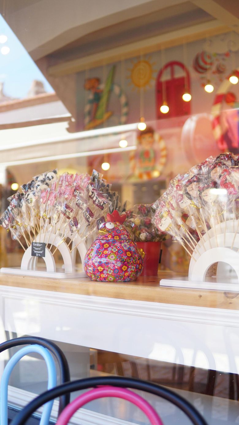 Exhibición colorida de dulces en el escaparate de una tienda, con piruletas y golosinas brillantes.