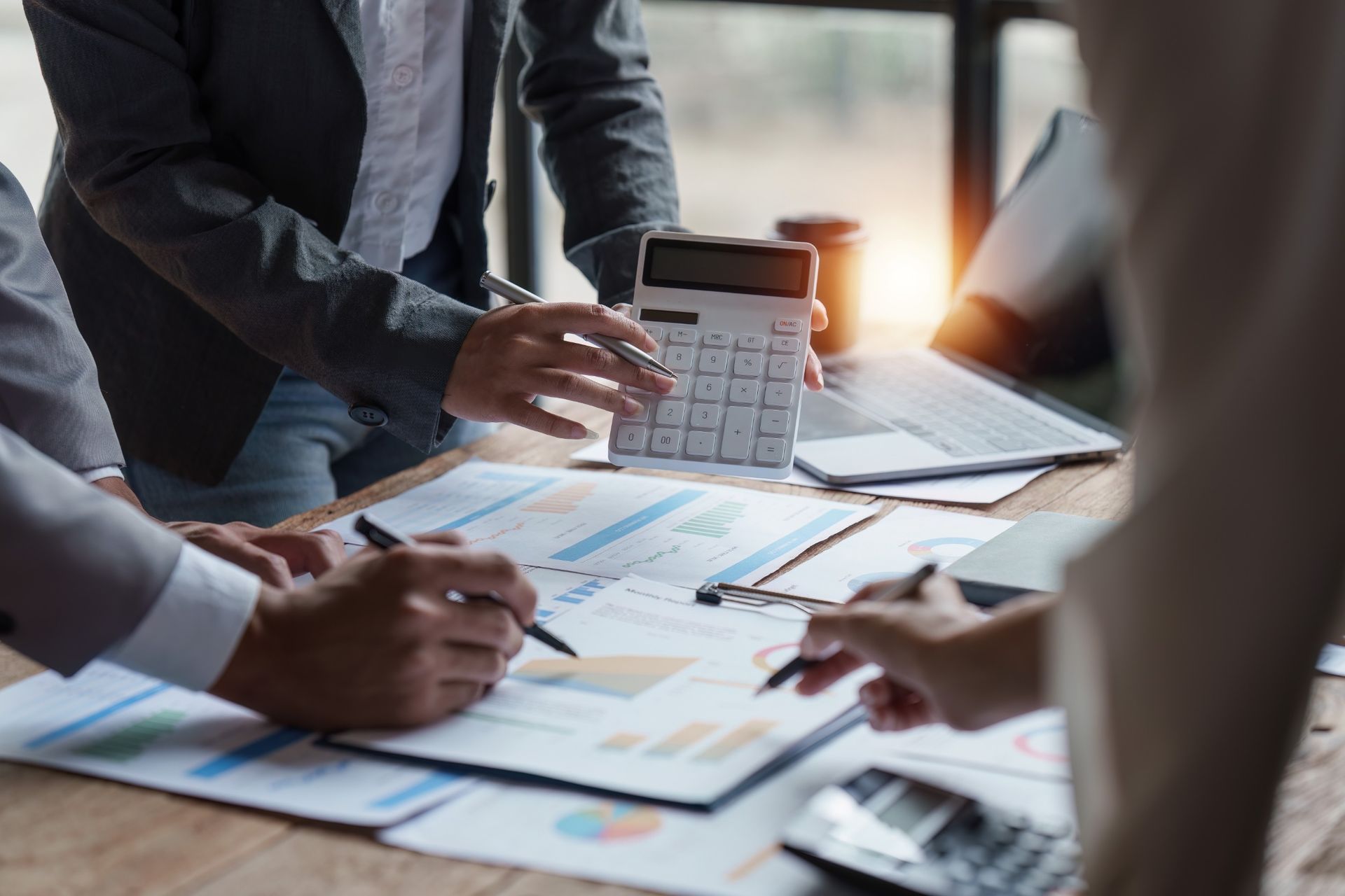 Equipo de negocios revisando datos financieros, utilizando calculadora y bolígrafos.