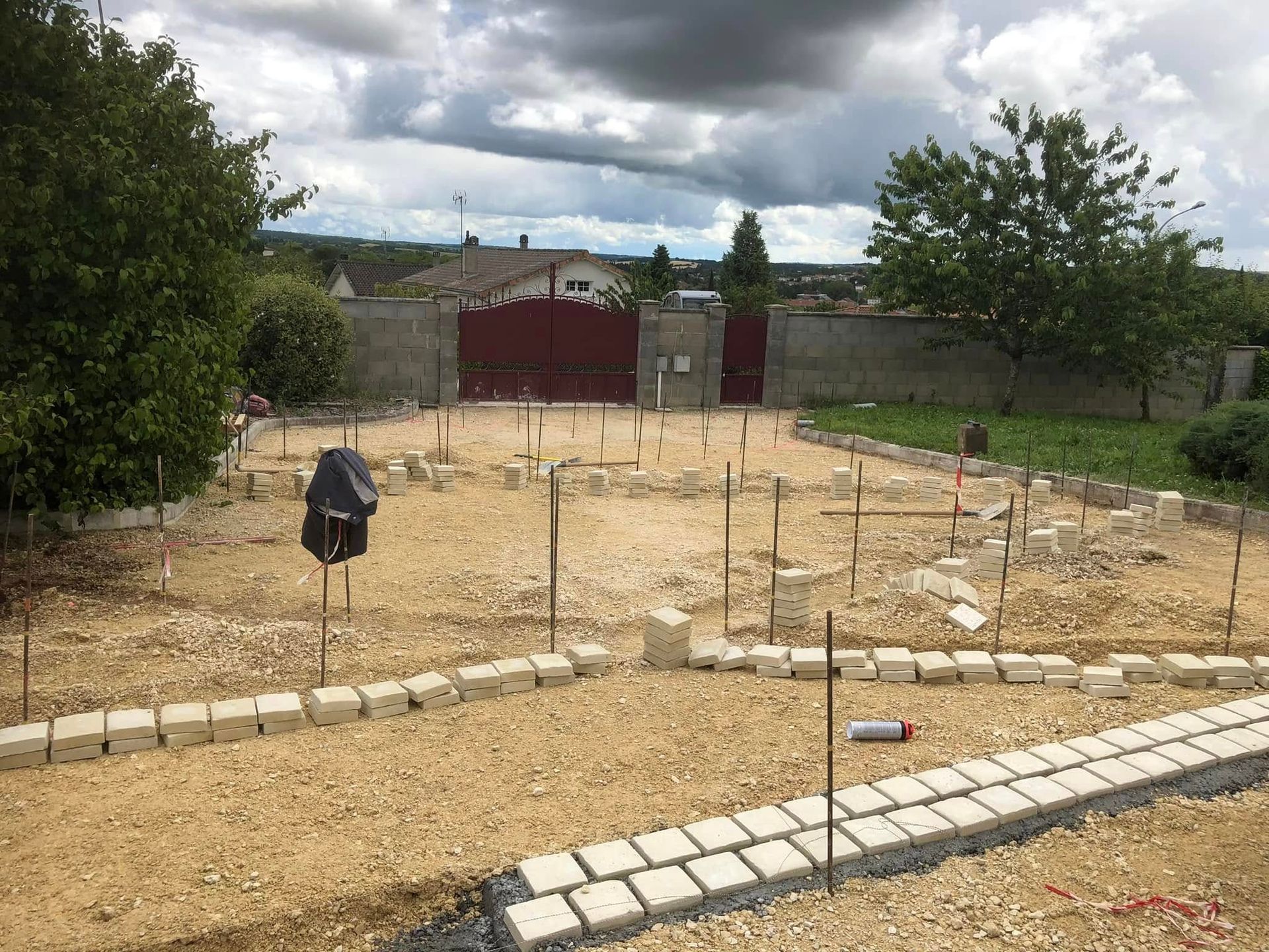 Un projet d'aménagement paysager extérieur montre des pavés clairs posés sur du gravier dans une cour.