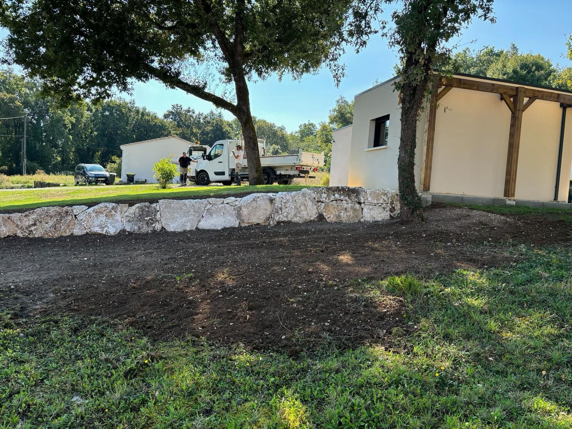 Un mur de soutènement en pierre sépare une cour.