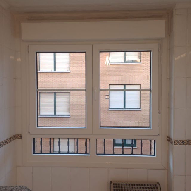 Un baño con una ventana que da a un edificio de ladrillo.