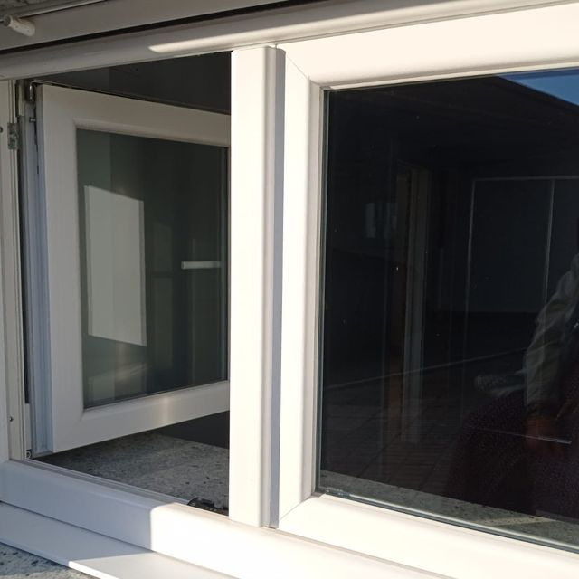 Una ventana blanca con el reflejo de una persona en ella.