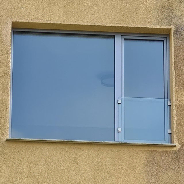 Una ventana grande en el costado de un edificio con una barandilla de vidrio.