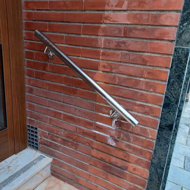 Una pared de ladrillos con una barandilla de metal fijada a ella.