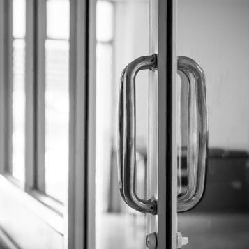 Una fotografía en blanco y negro de una puerta de vidrio con manija.
