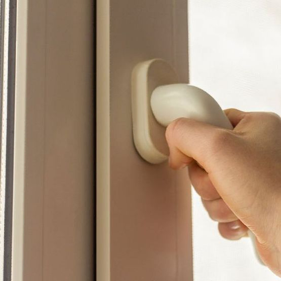 Una persona está abriendo una ventana con una manija blanca.