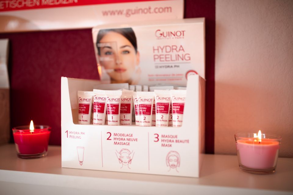 Produkte von Guinot und zwei brennende Kerzen