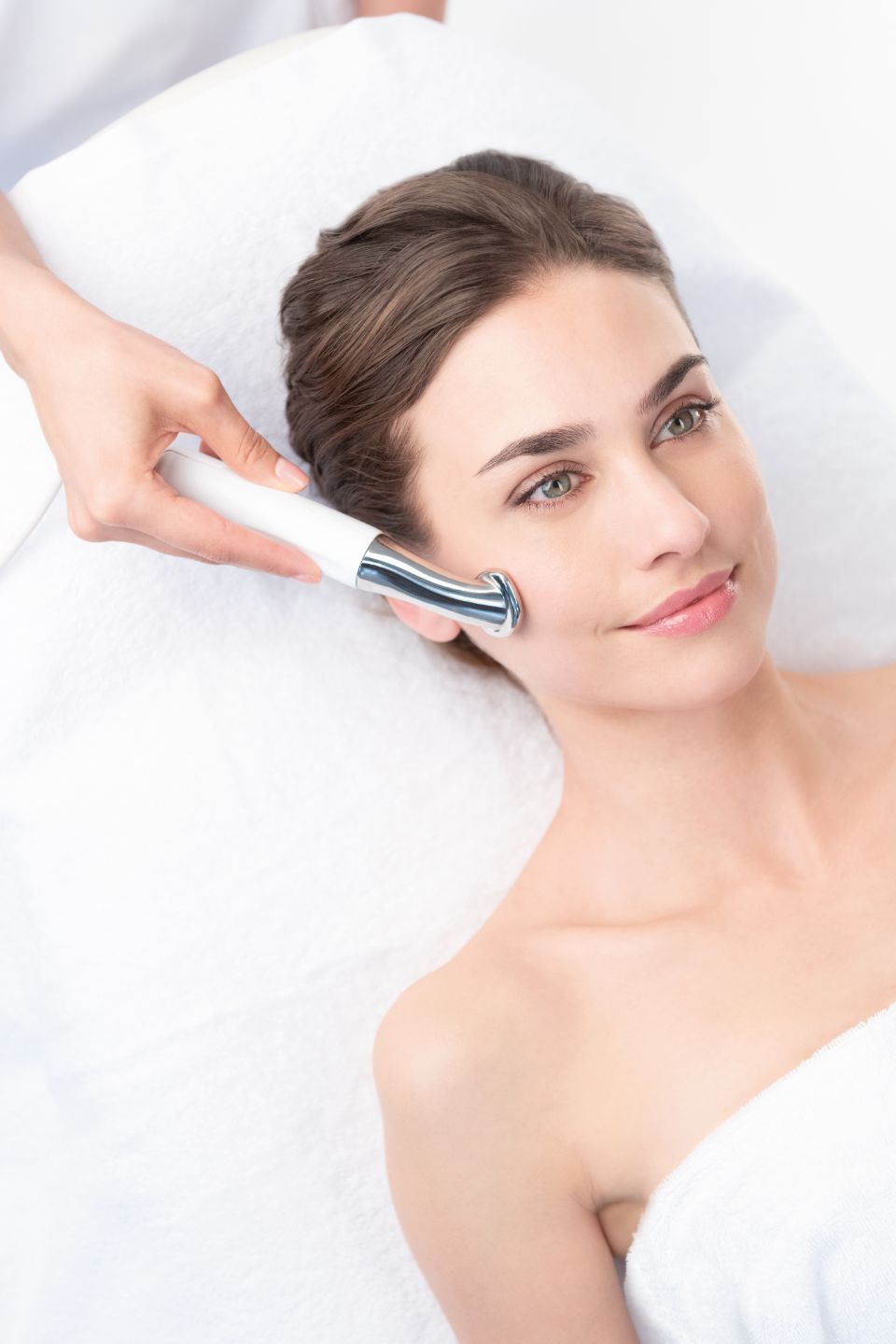 eine Frau wird mit einem Gerät im Gesicht behandelt