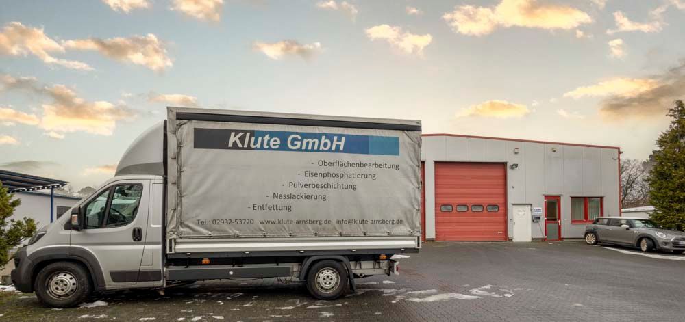 Ein LKW steht vor einem Gebäude mit einem roten Garagentor.