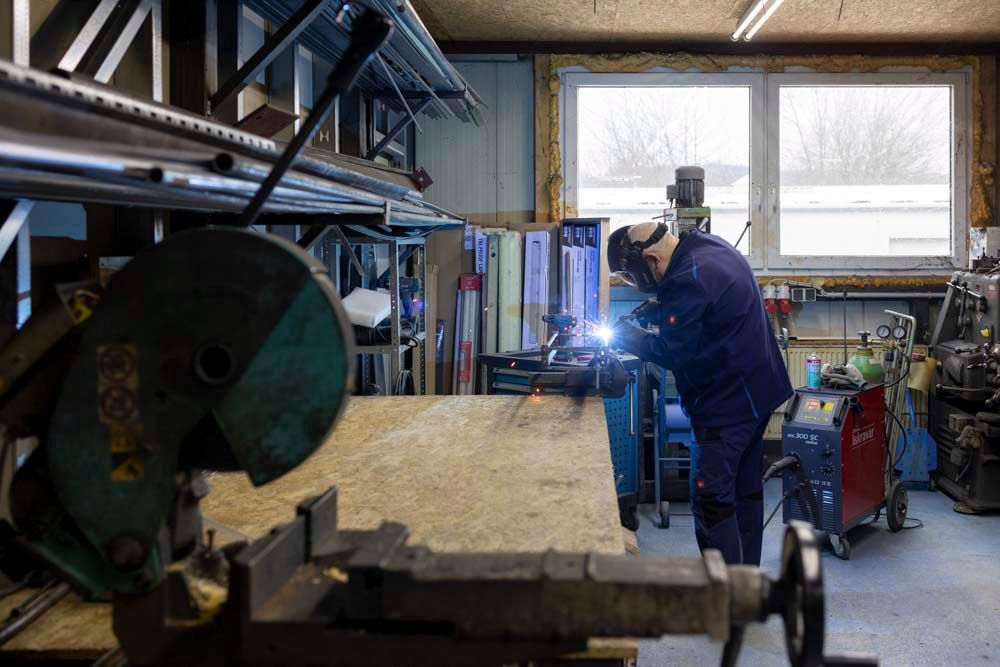 Ein Mann schweißt in einer Werkstatt ein Stück Metall.