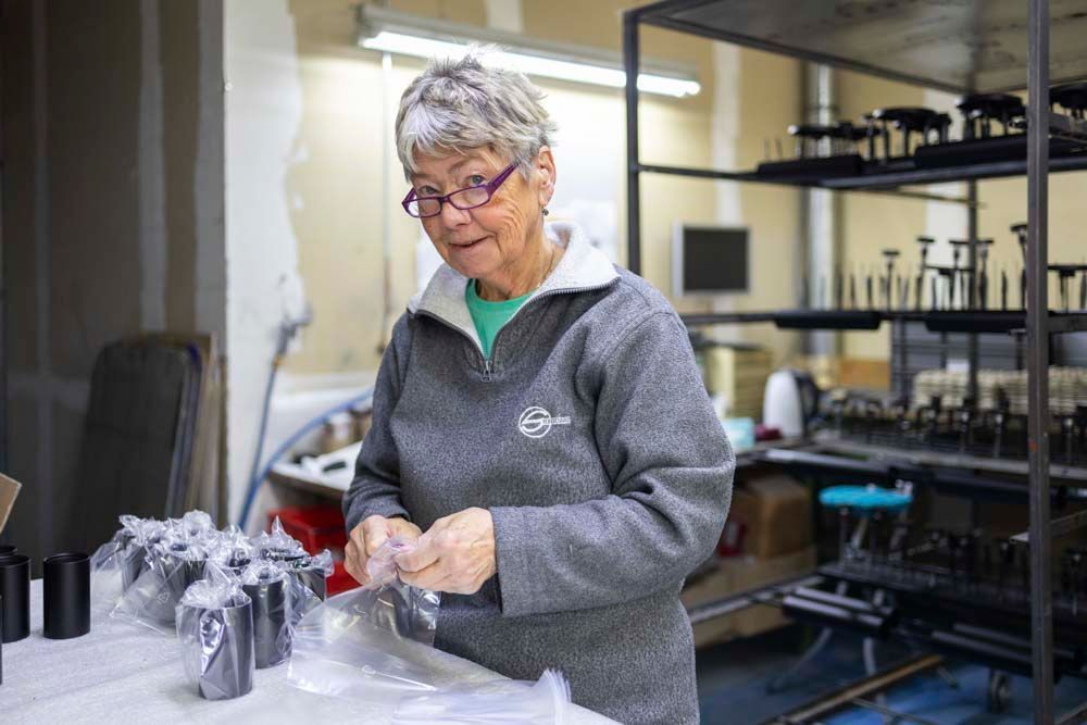 Eine Frau steht in einem Raum und verpackt Kerzen in Plastiktüten.