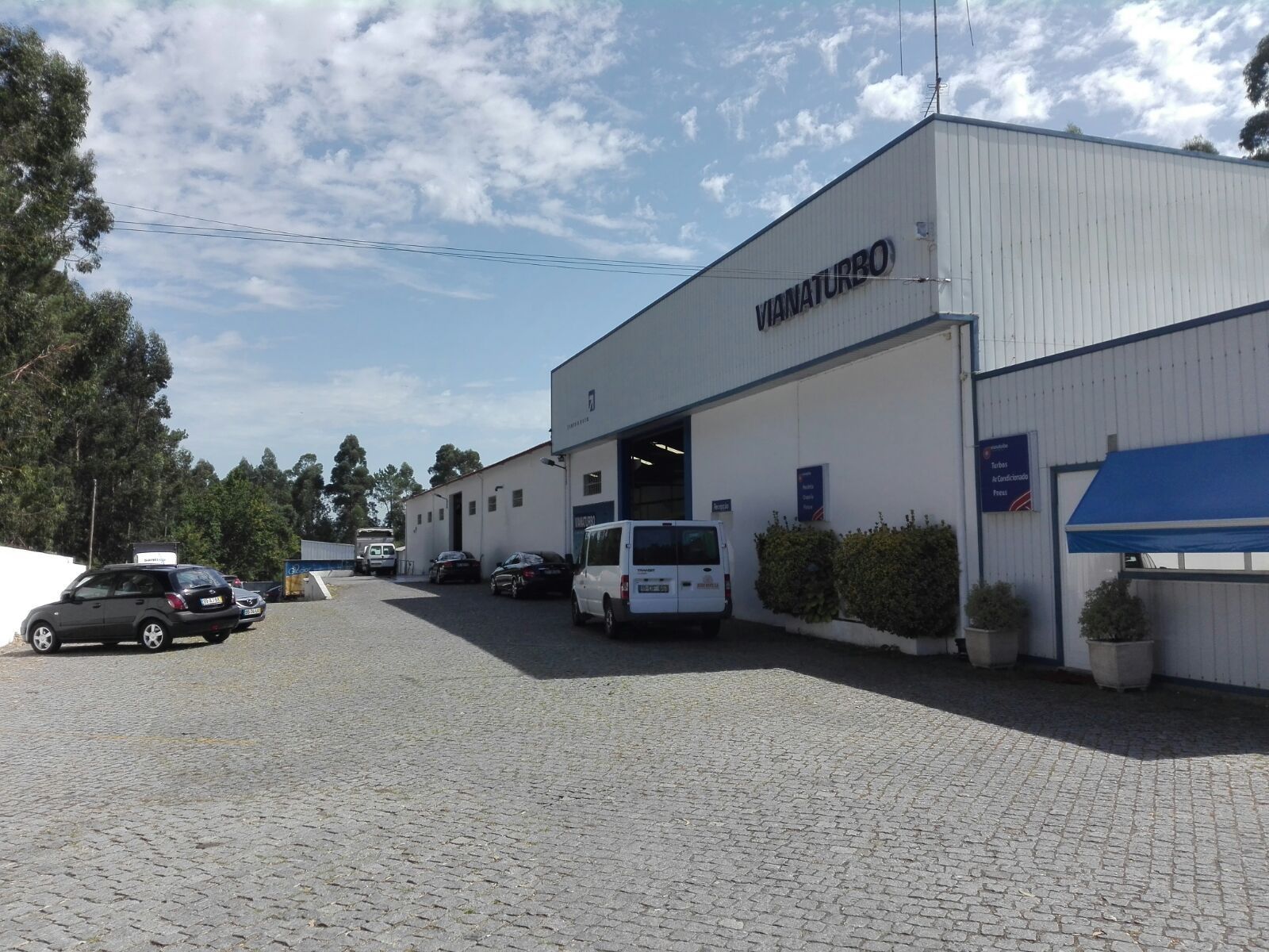 Uma van branca está estacionada em frente a um grande prédio branco