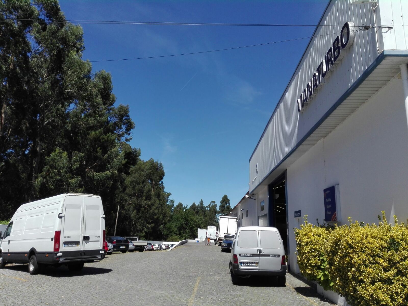 Várias vans brancas estão estacionadas em frente a um prédio que diz turbo
