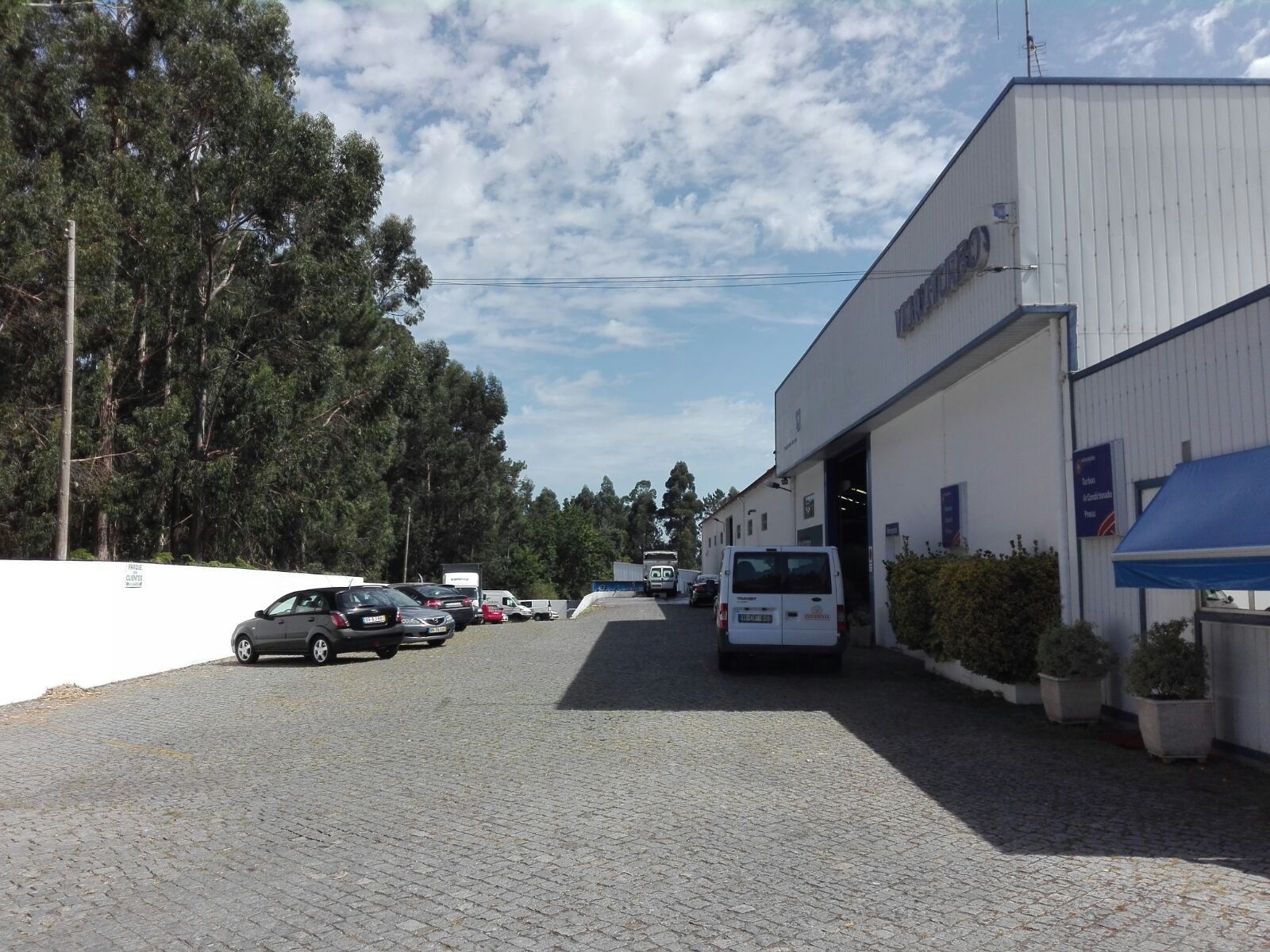 Uma van branca está estacionada em frente a um prédio branco