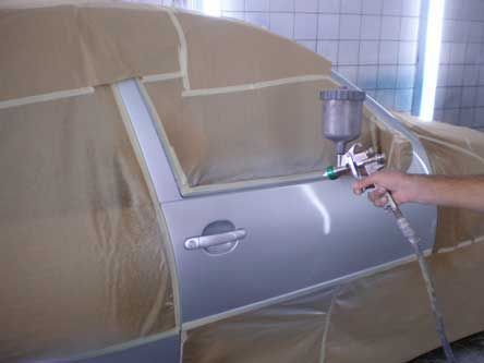 Uma pessoa está borrifando tinta na porta de um carro.