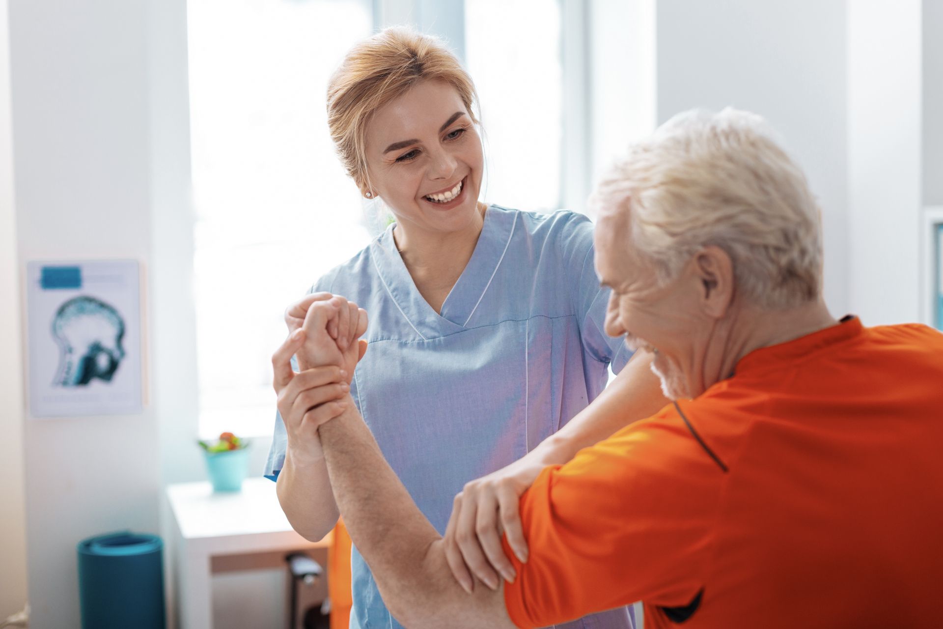 Une soignante aide un patient âgé lors de sa séance de rééducation de la main.