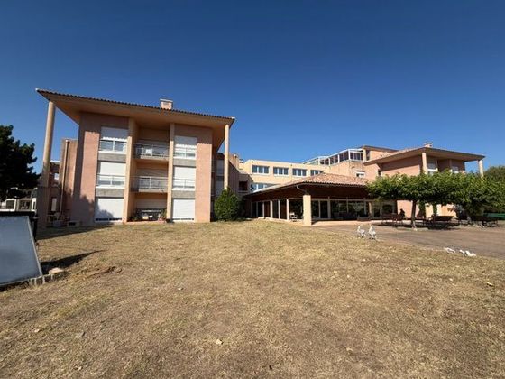 Immeuble moderne d'un EHPAD à plusieurs étages avec de grandes fenêtres et un premier plan herbeux sous un ciel bleu clair.
