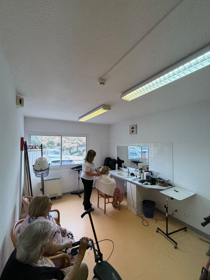 Salon de coiffure et de soins lumineux avec des résidents et le personnel.
