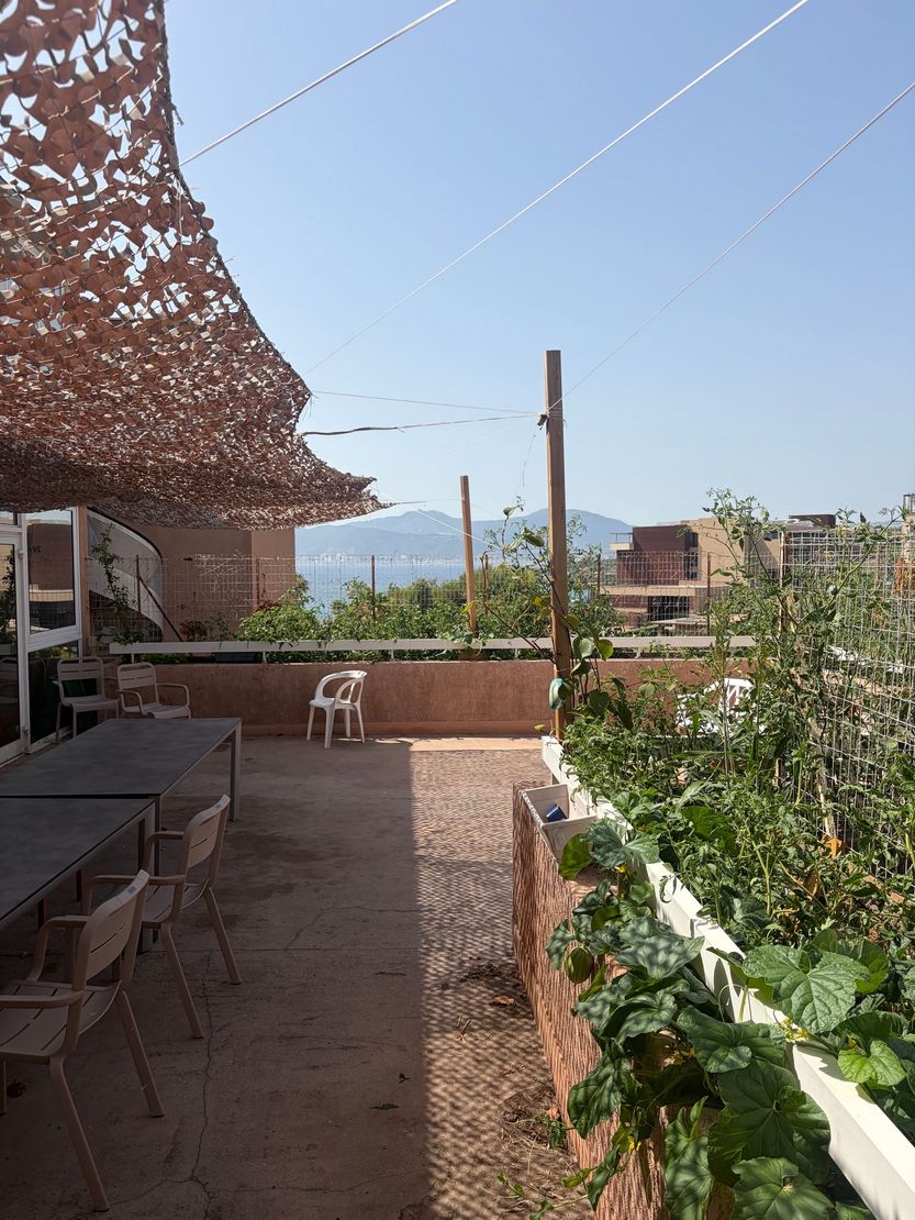 Terrasse ensoleillé avec plantes en pot, auvent ombragé et sièges extérieurs donnant sur les montagnes.