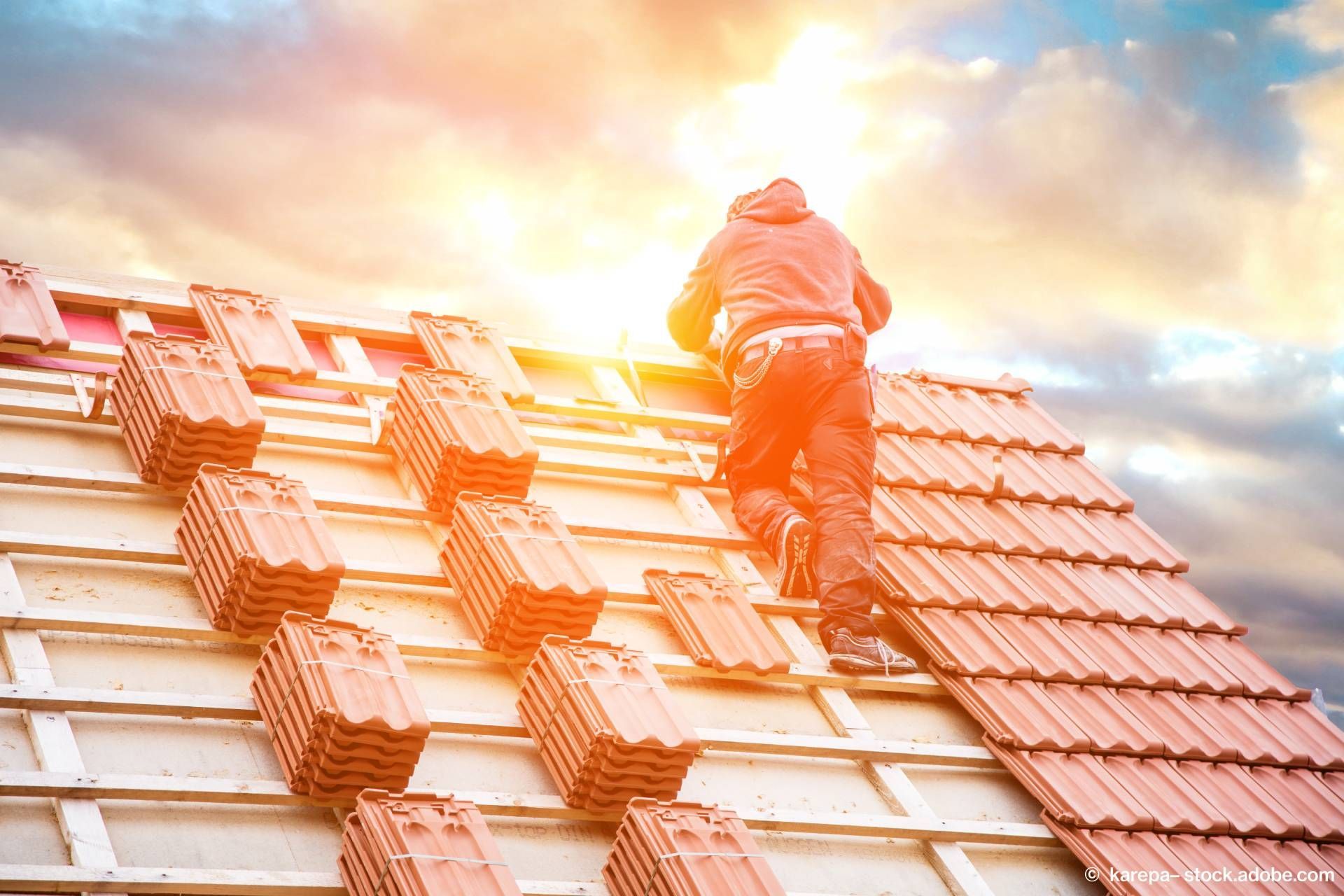 Mann bringt neue Schindeln an Dach an