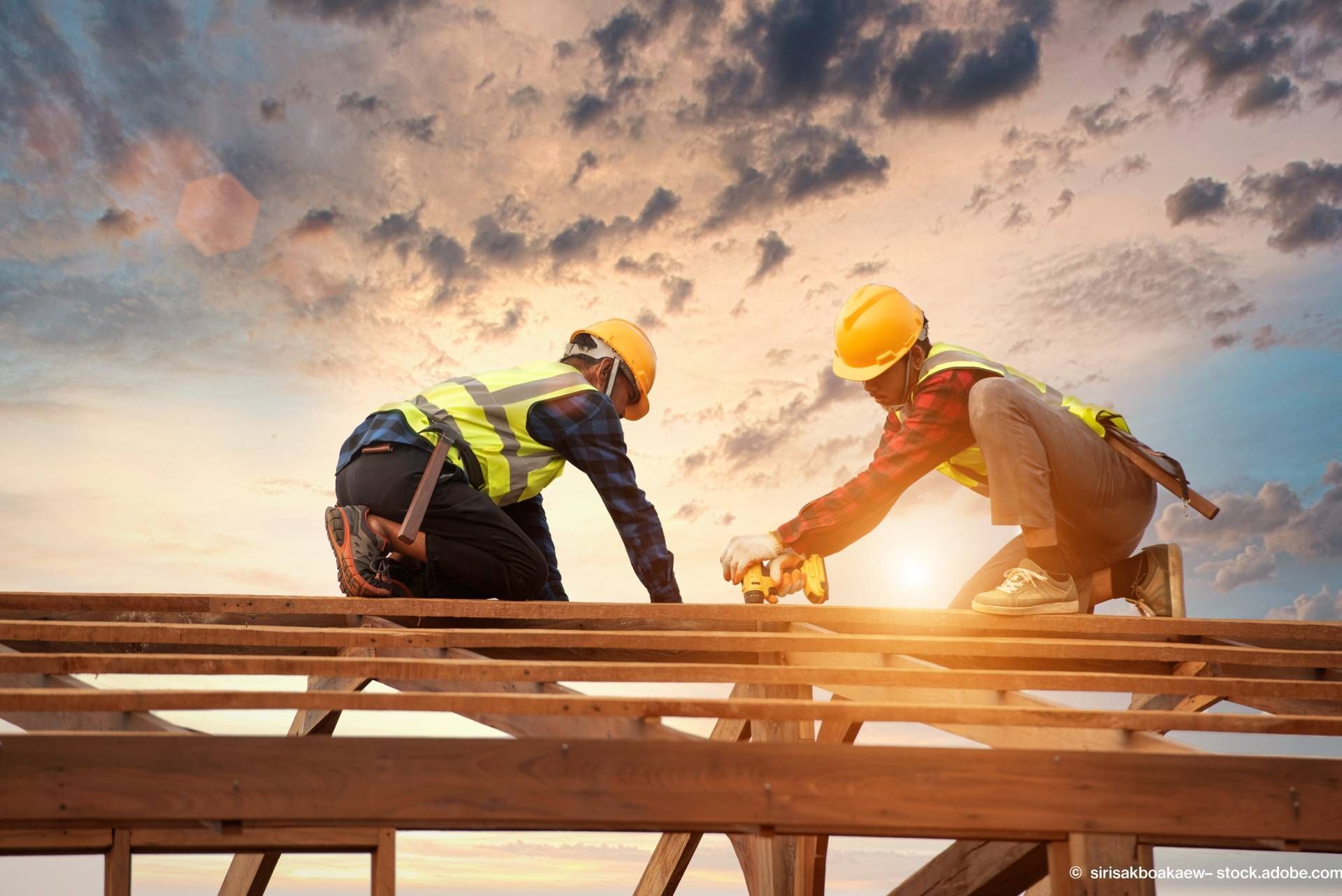 Zwei Männer arbeiten auf dem Holzgerüst eines Dachs