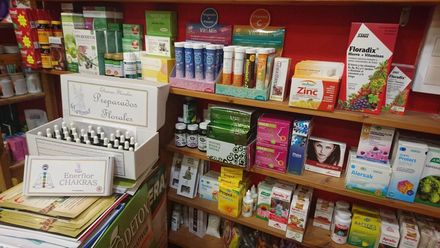 Estantes de suplementos y vitaminas en una tienda, con una caja blanca de viales en primer plano.