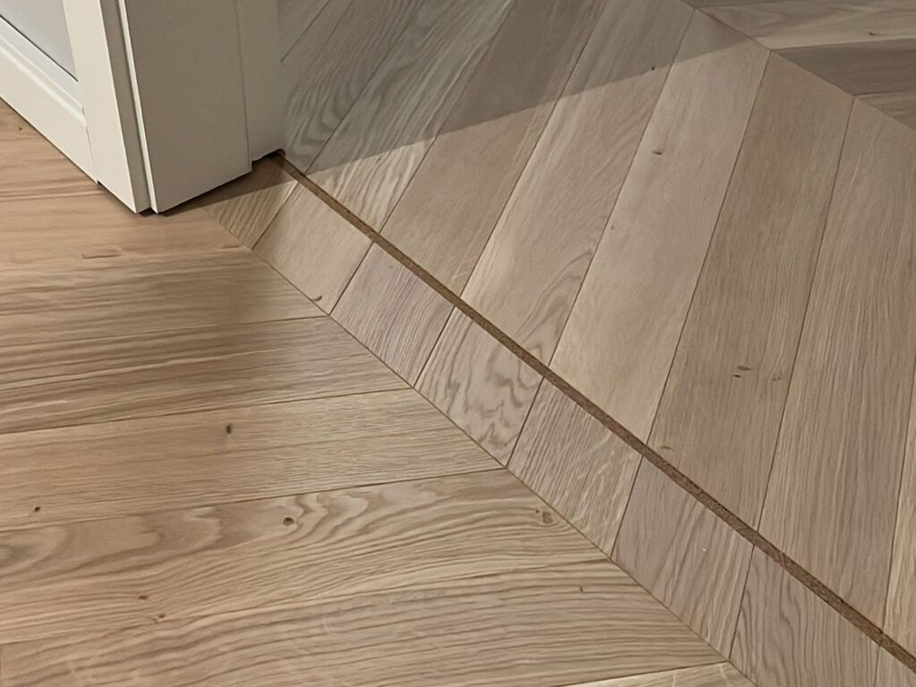 Eine Nahaufnahme eines Holzbodens mit einem Chevron-Muster.