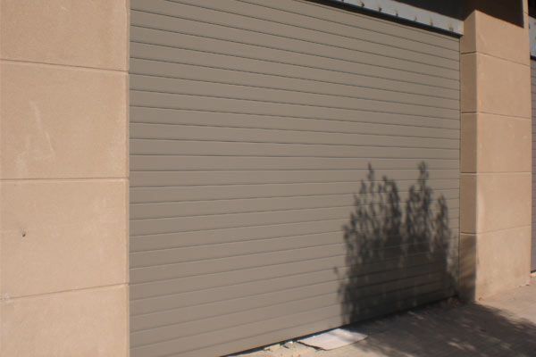 Una puerta de garaje con la sombra de un árbol sobre ella.