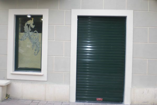 Un edificio con una puerta verde y una ventana.