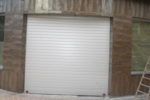 Una puerta de garaje blanca está en el costado de un edificio.