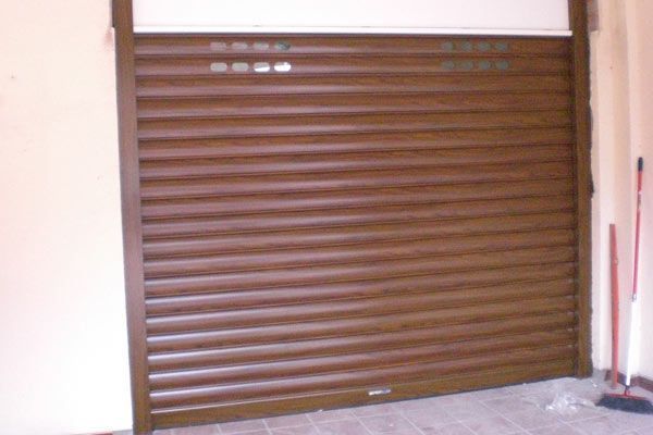 Una puerta de garaje de madera está en una habitación al lado de una escoba.