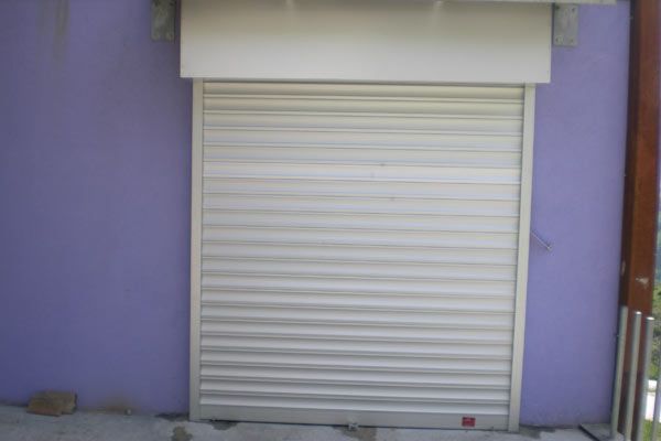 Una persiana blanca está sobre una pared violeta.