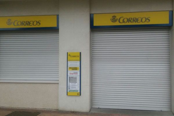 Un edificio con un cartel amarillo que dice correos