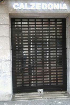 Un escaparate con una persiana negra y un cartel que dice Calzedonia.