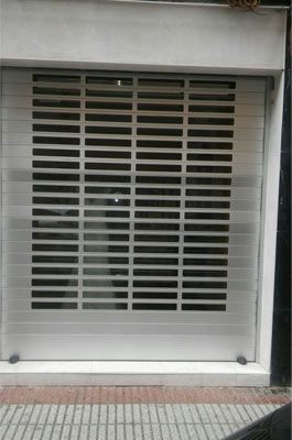 Un local comercial con una puerta de garaje corrediza y un coche aparcado delante de ella.