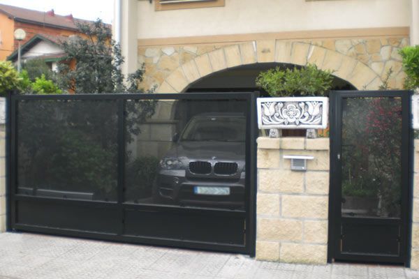Un BMW está estacionado en una entrada detrás de una valla.