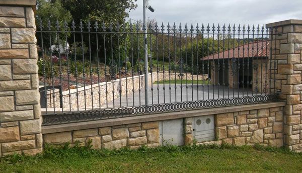 Un muro de piedra con una valla de hierro forjado que lo rodea.