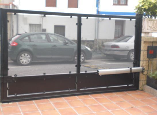 Un coche verde está aparcado detrás de una puerta negra.