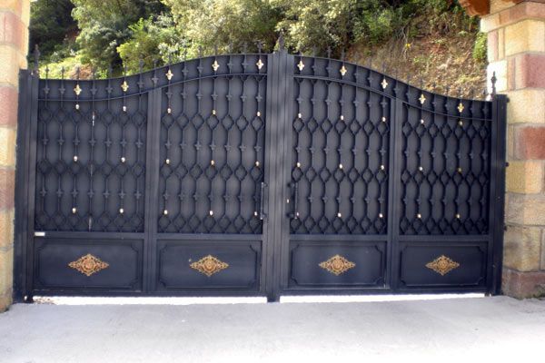 Una puerta de hierro forjado negro se encuentra frente a una pared de ladrillos.