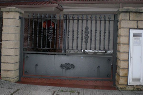 Una puerta de hierro forjado está frente a un edificio de ladrillo.